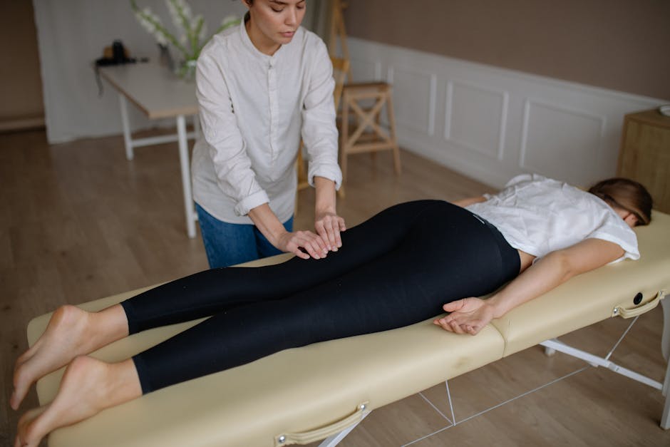 Woman lying face down on massage table getting a therapeutic massage in a calm spa environment.