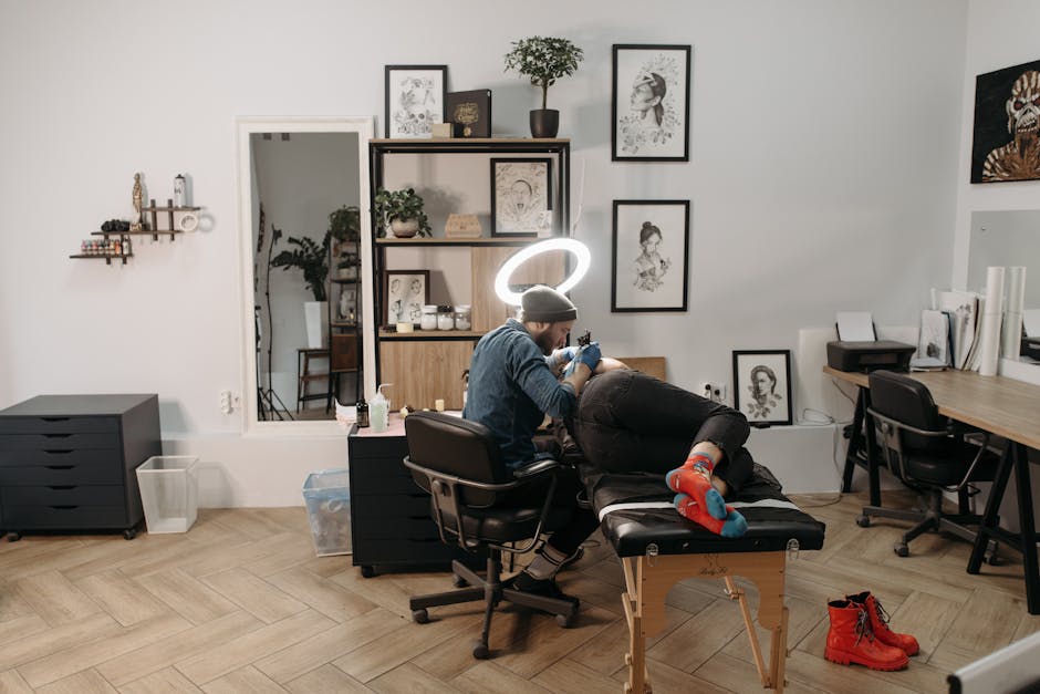Tattoo artist using a tattoo machine in a stylish studio, focusing on intricate design.