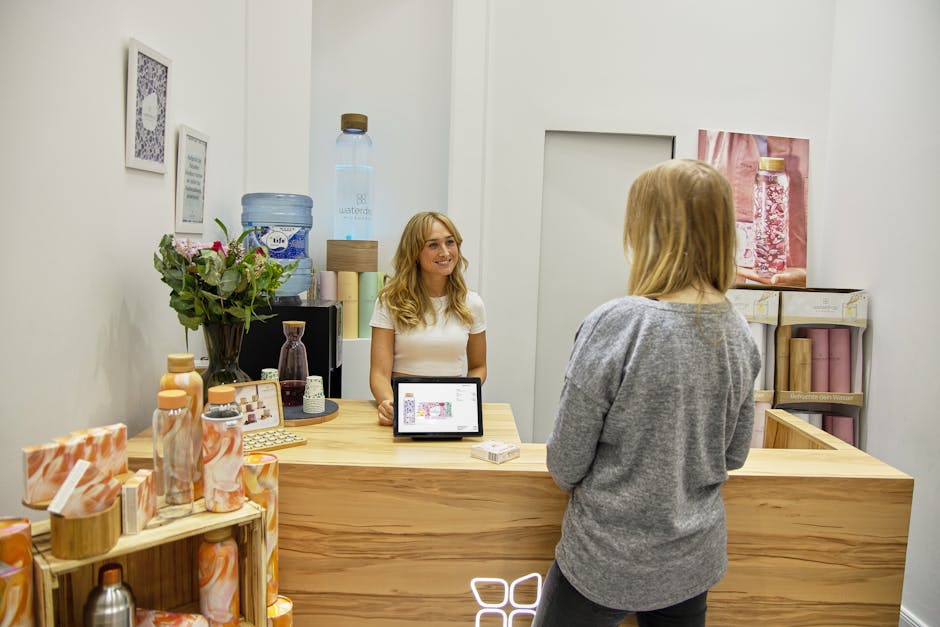 Smiling receptionist interacting with a customer in a bright and modern beauty clinic reception area.