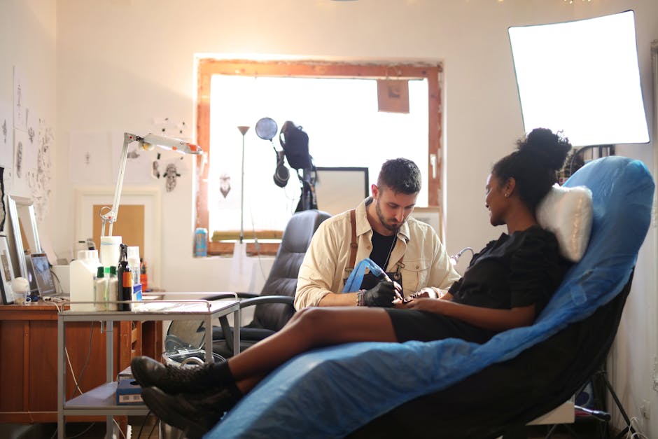 A tattoo artist working on a client's arm in a well-lit modern studio.