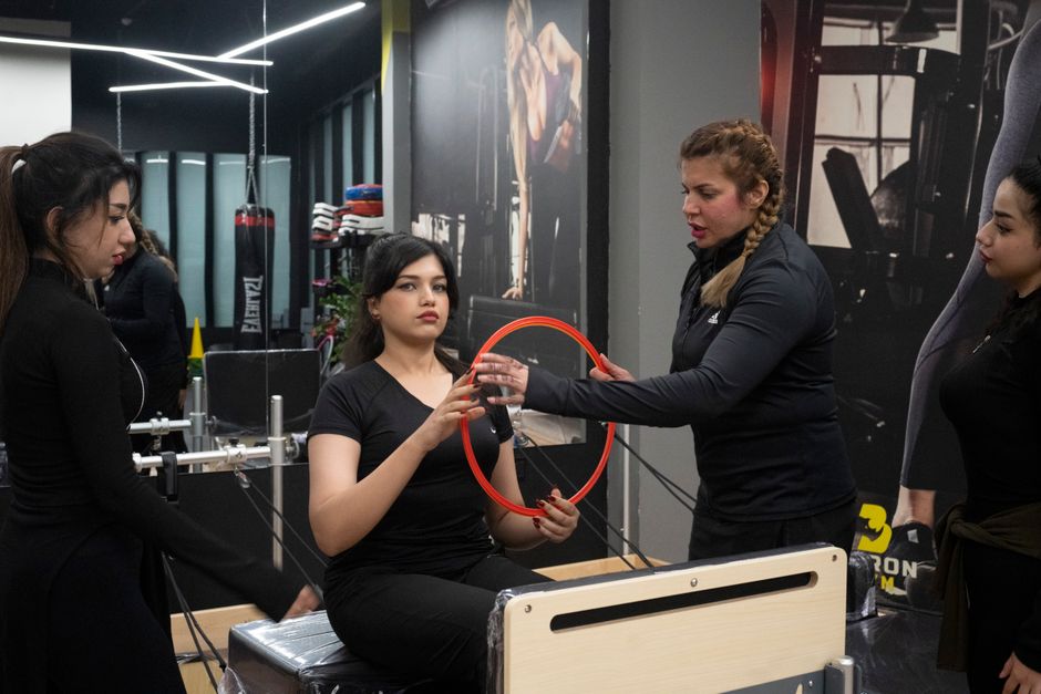 Women in a fitness class using Pilates equipment indoors. Enthusiastic and engaging session for health and fitness.